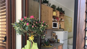 Une cuisine avec des meubles en bois, un four à micro-ondes et une plante aux fleurs roses.