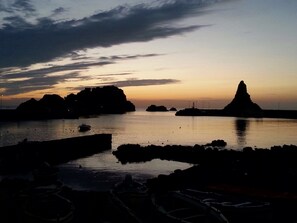 Et kystlandskab med både fortøjet nær klippeformationer ved solnedgang.