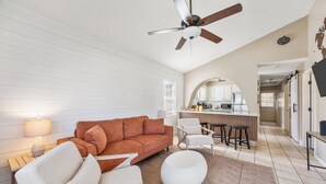 Un salon moderne avec un canapé, des fauteuils, une table basse et un ventilateur de plafond.