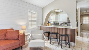 Une cuisine moderne dotée d’un îlot central, de tabourets de bar et d’un coin repas avec un canapé et des chaises.
