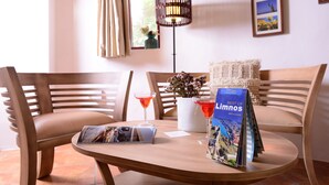 Een houten tafel met een tijdschrift, een glas rode drank en een lamp.