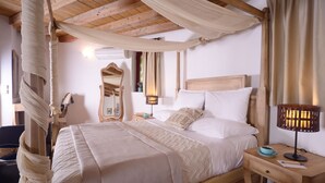 Een slaapkamer met een hemelbed, een nachtkastje met een lamp en een spiegel.