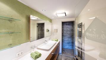 Un baño moderno con un espejo grande, dos lavamanos y una cabina de ducha de vidrio.