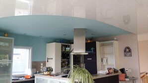 Une cuisine avec un plafond de couleur turquoise, des armoires blanches et une hotte de cuisine centrale.