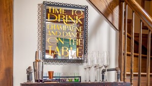 Een bar met een spiegel waarop staat: 'TIJD OM CHAMPAGNE TE DRINKEN EN OP DE TAFEL TE DANSEN'.