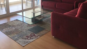 A living room with a glass coffee table, a red sofa, and a patterned rug. - Marina View apartment with personal WiFi & UK TV (Unknown)