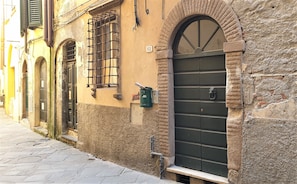 Una calle estrecha con edificios históricos, un buzón y una puerta con reja de metal.