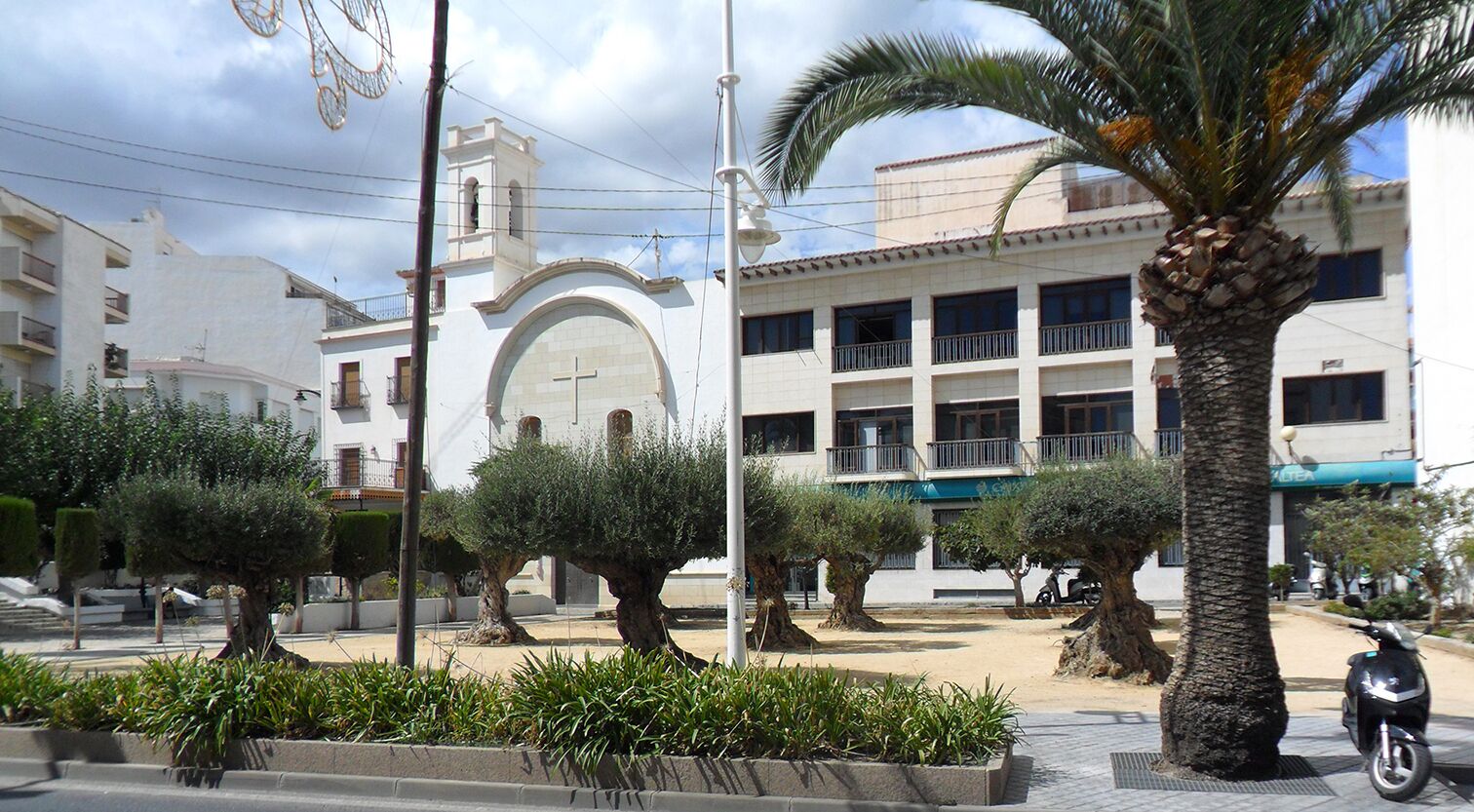A public square with palm trees, a church, and a building with balconies.