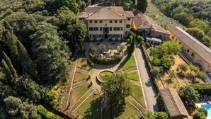 Vue aérienne d’une grande villa dotée d’une cour intérieure, entourée d’une végétation luxuriante et d’arbres.