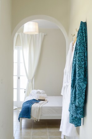 Ein Schlafzimmer mit Bett, Kleiderhaken und einem Fenster mit Vorhängen.