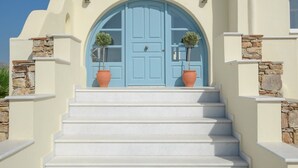A building with a blue door, white stairs, and potted plants.