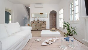 A spacious living room with a white sofa, a wooden cabinet, and a large mirror.