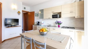 Cocina moderna con comedor, que incluye un televisor, un cuenco de fruta y una estufa a gas.