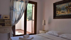 Habitación de hotel con cama, mesita de noche, lámpara, un cuadro y vistas por la ventana.