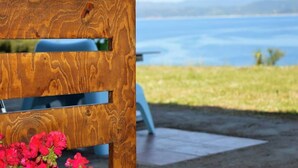 Una estructura de madera con listones horizontales y una superficie reflectante, con vistas a un cuerpo de agua y vegetación.