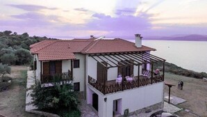 Una casa de dos pisos con balcón, terraza y vista al mar.