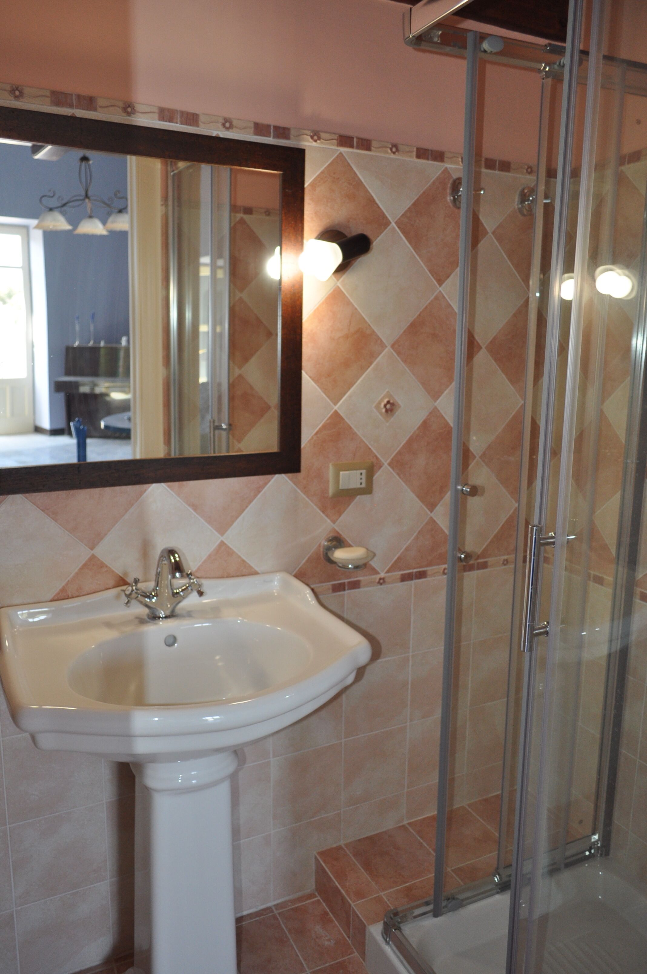 Een badkamer met een wastafel, spiegel en douche.