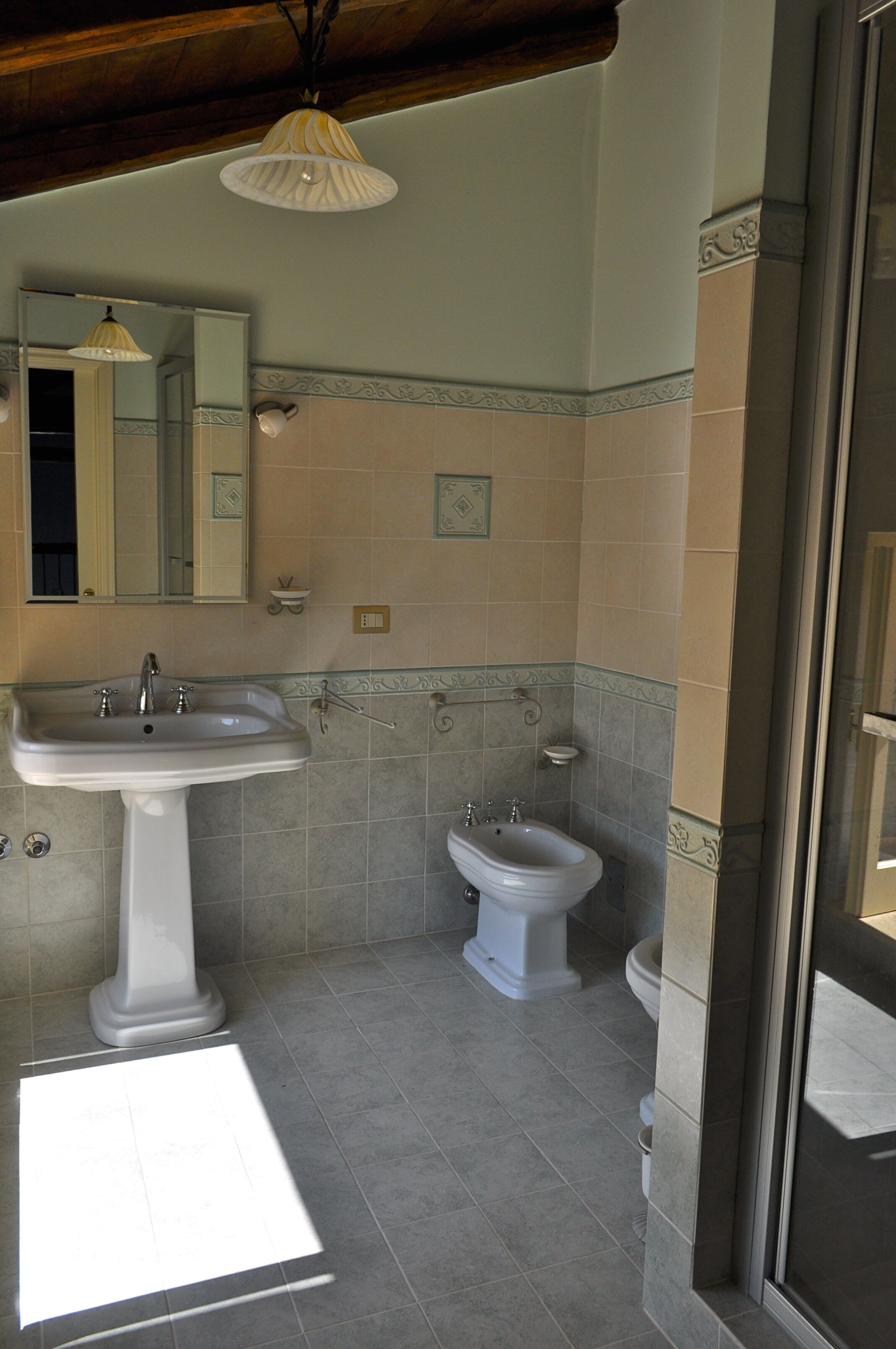 Ein Badezimmer mit einem Waschbecken auf Säule, einem Bidet und einem Spiegel.