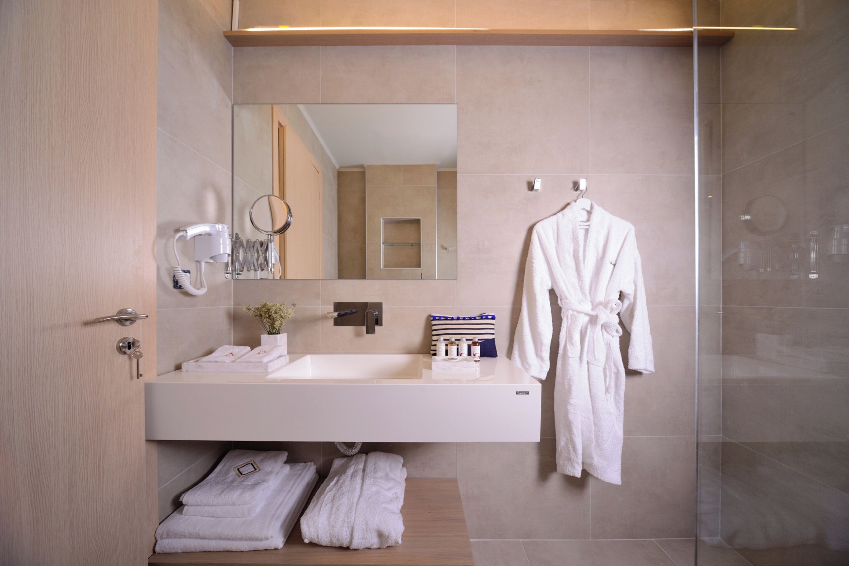 Une salle de bain moderne avec un grand miroir, un lavabo blanc et une douche à parois de verre.