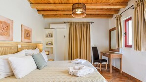 A hotel room with a bed, a desk, a chair, a mirror, and a ceiling light. - Superior Suite with Sea View / Varos Village Boutique Hotel (Lemnos)