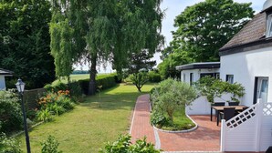 A well-maintained garden with a brick pathway leading to a white building with a patio.