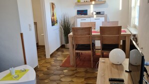 A modern living room with a wooden dining table, chairs, a sofa, and a TV.
