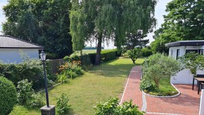 A well-maintained garden with a brick pathway, various shrubs, and a lawn.