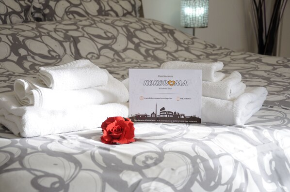 A neatly made bed with folded towels and a brochure on it. - Kokoroma Apartment Vatican area Rome (Roma)