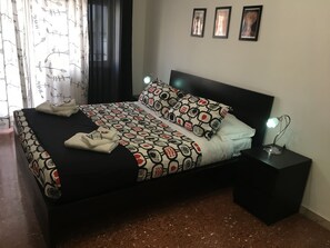 A neatly made bed with patterned bedding, a bedside lamp, and a small table with a lamp. - Kokoroma Apartment Vatican area Rome (Roma)