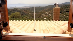 Vista desde una ventana con marco de madera y un paisaje montañoso.
