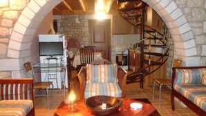 Una sala de estar acogedora con un arco de piedra, un comedor con muebles de madera y una cocina al fondo.