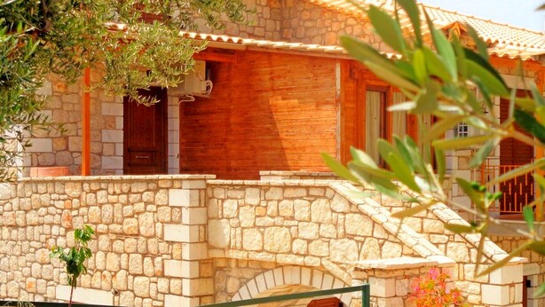 Un edificio de piedra con fachada de madera, una escalera de piedra y una barandilla de metal.