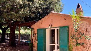 A small building with green shutters, a door, and a window.