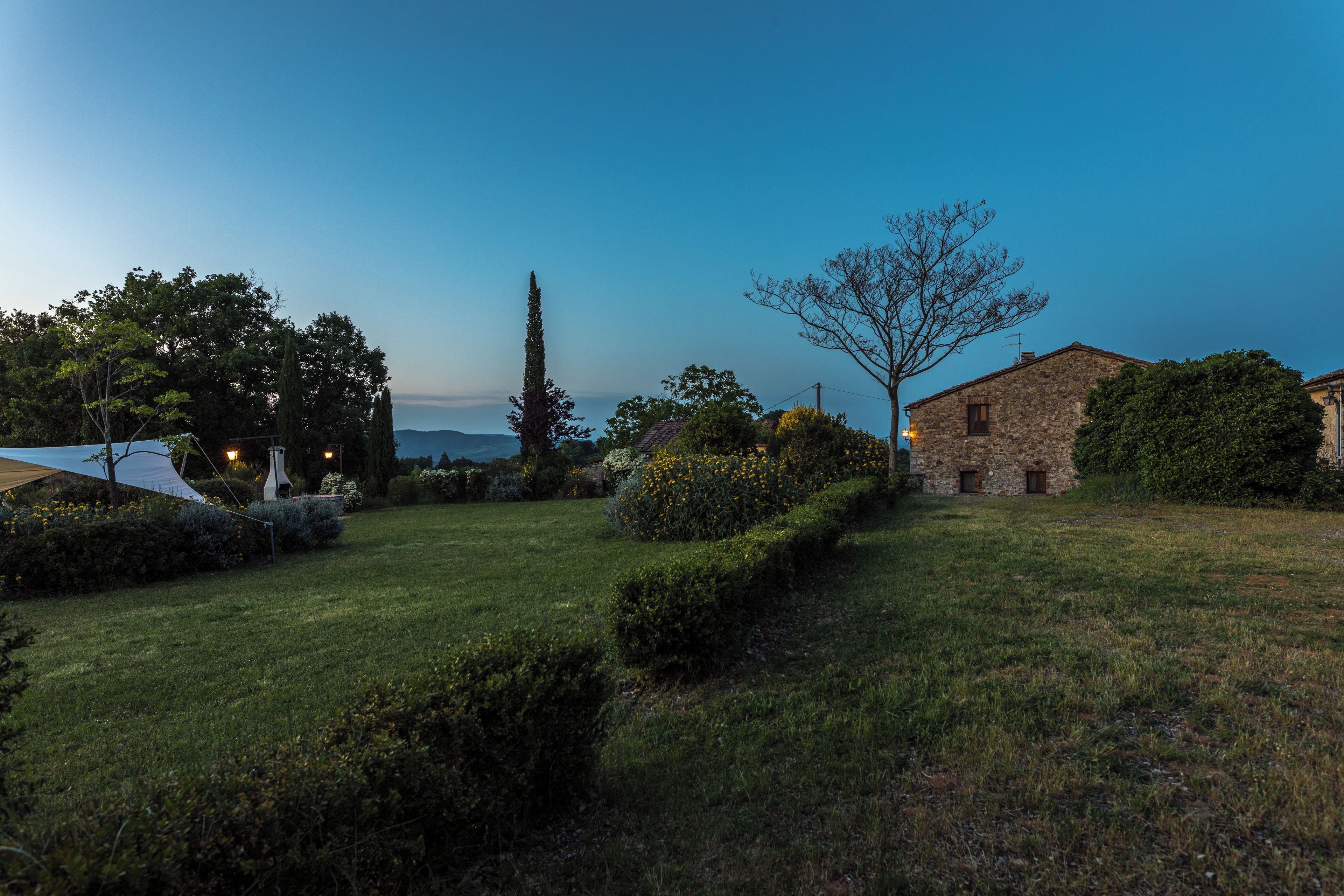 A grassy outdoor area with a stone building, a tree, and a lamp post.