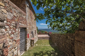 A stone building with a door and steps leading to a balcony overlooking a mountainous landscape. - Cozy Cottage (A1) with pool - Le Caldanelle (Civitella paganico, Grosseto)