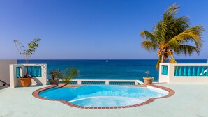 A pool with a view of the ocean and a sailboat in the distance.