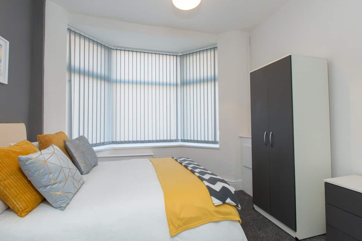 A bedroom with a bed, a wardrobe, and a window with blinds.