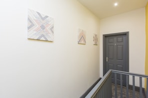 Stylish hallway with abstract artworks and a dark door leading to a staircase.