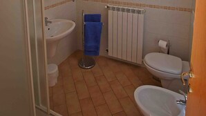 A bathroom with a shower, sink, toilet, and bidet.