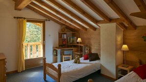 Un dormitorio acogedor con techo de madera, una cama con almohadas, un escritorio con silla y una ventana con cortinas.