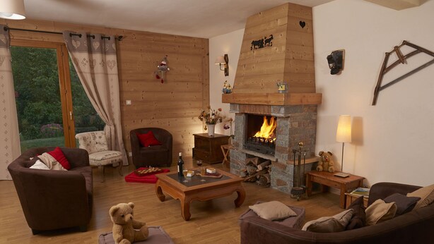 Una sala de estar acogedora con chimenea, paredes de madera y asientos cómodos.