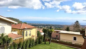 A residential area with houses, a clear sky, and a distant view of the sea.