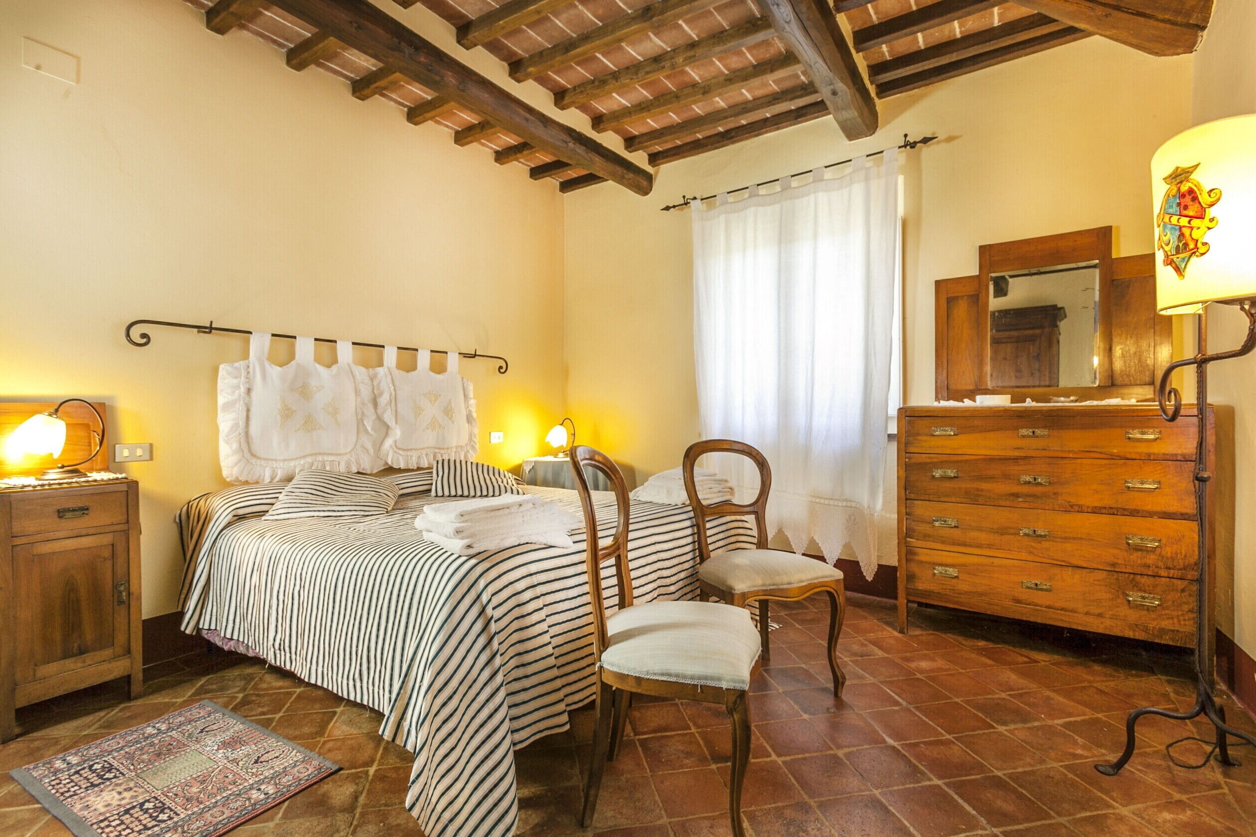Un dormitorio con cama, dos sillas, cómoda y espejo.