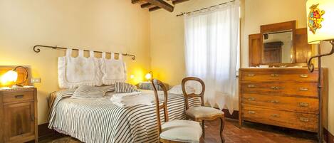 Un dormitorio con cama, dos sillas, cómoda y espejo.