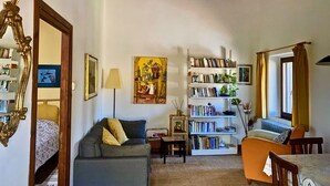 Una sala de estar acogedora con un sofá, una estantería y una mesa de comedor.