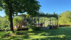 Un jardin agrémenté d’une pergola, d’une fontaine et de mobilier d’extérieur.