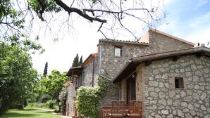 Un edificio de piedra con patio y mobiliario exterior.