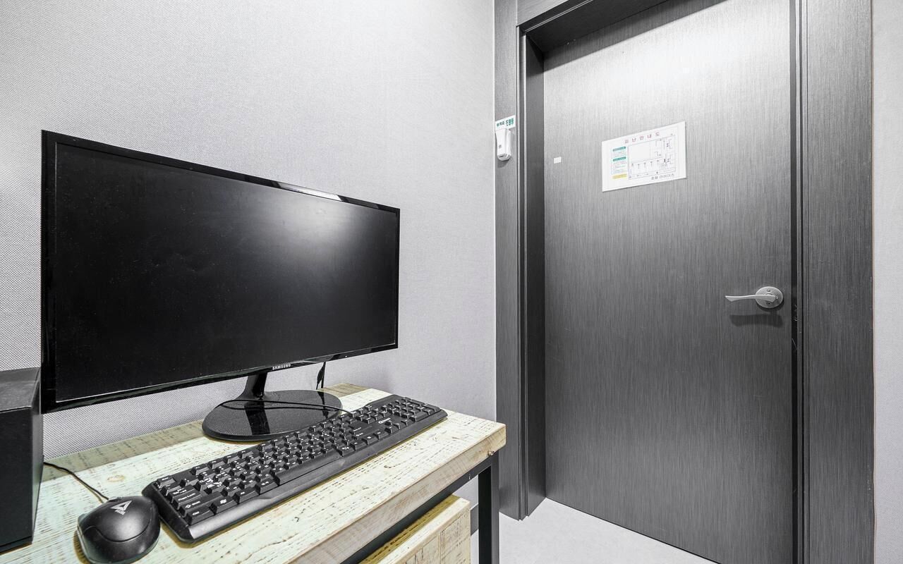 Un escritorio con monitor, teclado y ratón, y una puerta cerrada con cerradura.