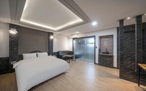 A modern bedroom with a bed, a bench, a glass door, and a marble wall.