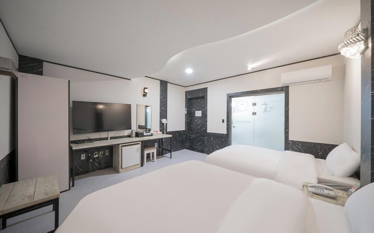 Une chambre d’hôtel moderne équipée d’un grand lit, d’une télévision, d’un bureau et d’une salle de bain.
